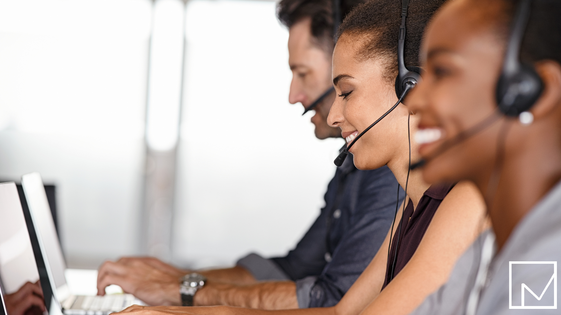 Three focused sales professionals wearing headsets, sitting side by side and actively engaged in calls, demonstrating productivity and team driven results.