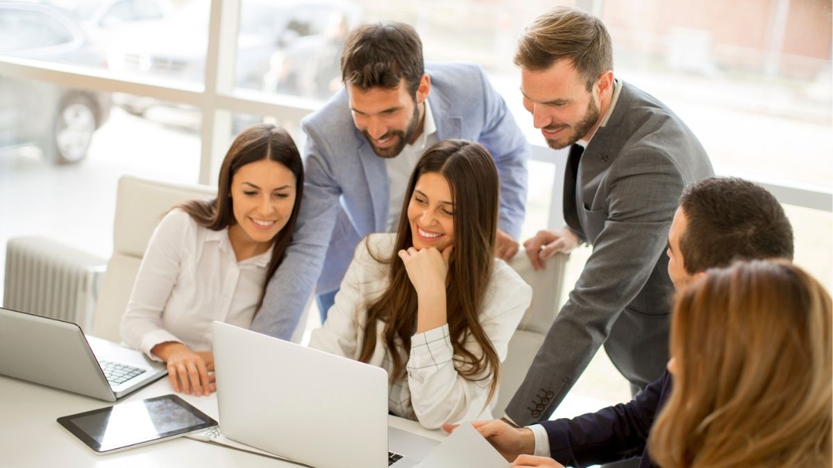Team reviewing data on laptops in office, representing balancing competitive rates and profit margins in a staffing agency.