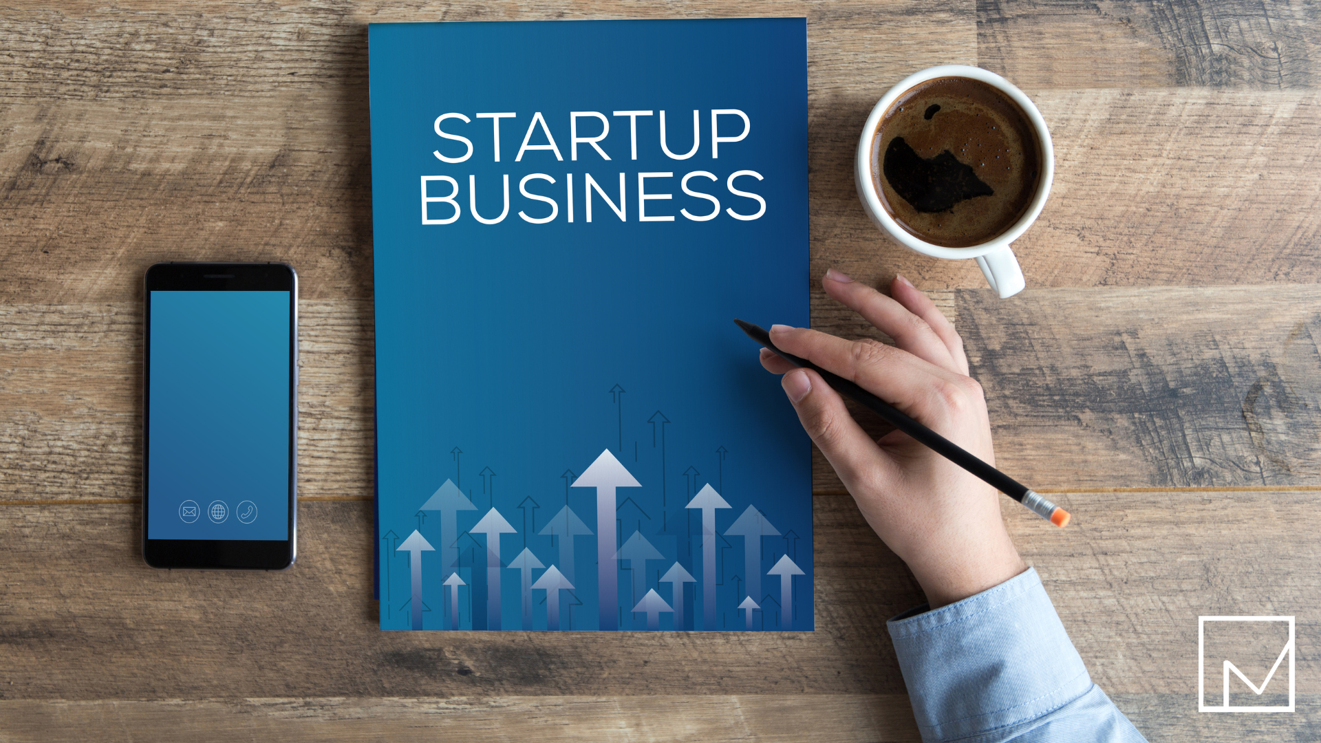 Person sitting at a coffee table with a book titled 'How to Start a Business,' a cup of coffee, and a phone preparing to launch their staffing company.