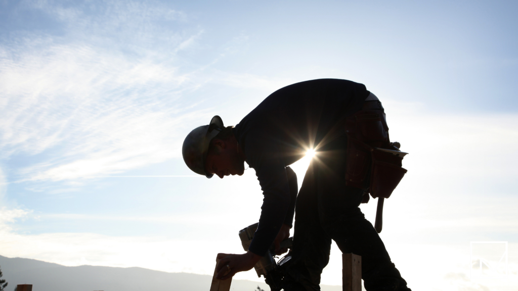 onstruction worker operating machinery on a worksite, illustrating the importance of workers’ comp for safety and risk management in hazardous job environments.