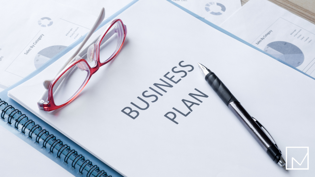 A business plan document with a pen and reading glasses resting on top, symbolizing the process of writing a business plan for staffing firms.
