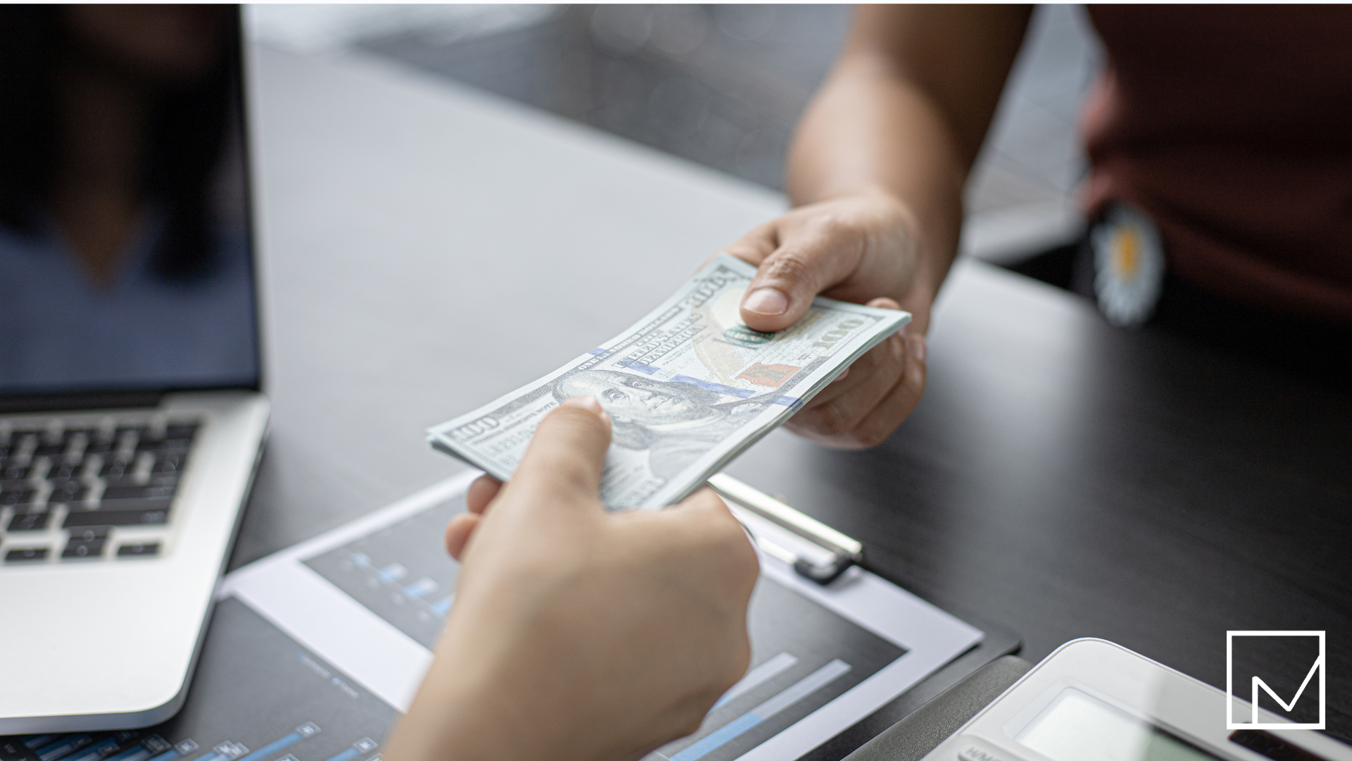 Businessperson handing money to another across a table, symbolizing how staffing agencies earn revenue when first starting out.