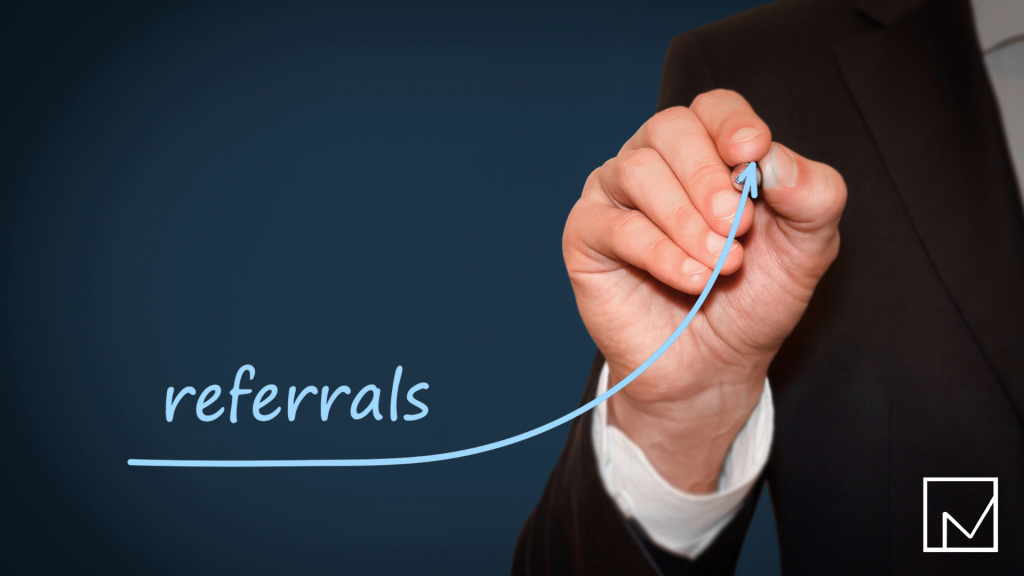 Man’s hand drawing the word 'referrals' inside an upward-pointing arrow on a whiteboard.