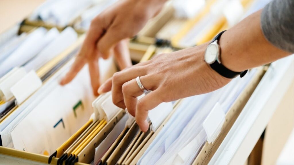 Person organizing business files in a filing cabinet, representing choosing the right legal structure such as LLC or S corporation for a staffing firm.