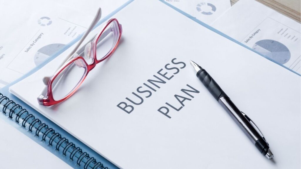 Business plan document with charts, pen, and glasses on a desk, representing strategic planning and growth for staffing agency success.