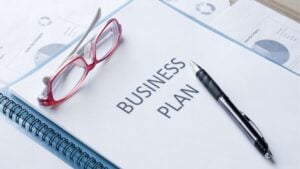 Business plan document with charts, pen, and glasses on a desk, representing strategic planning and growth for staffing agency success.