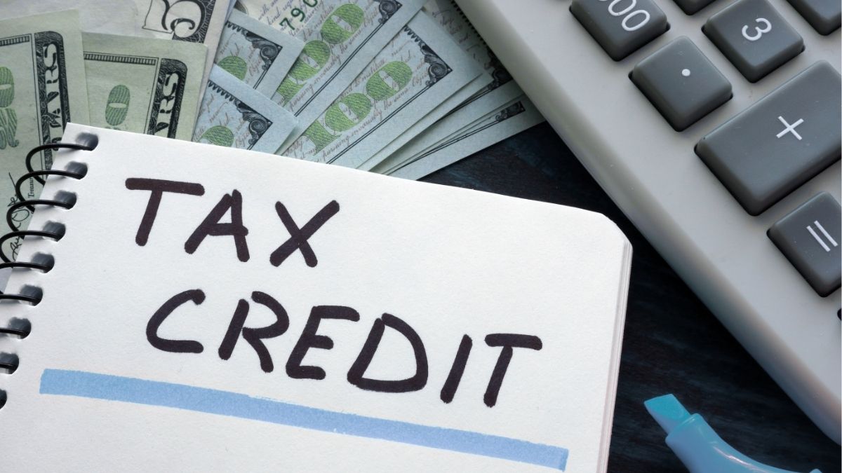 Notebook labeled “Tax Credit” next to cash and calculator, representing the Earned Income Tax Credit and its financial benefits for staffing firms and employees.