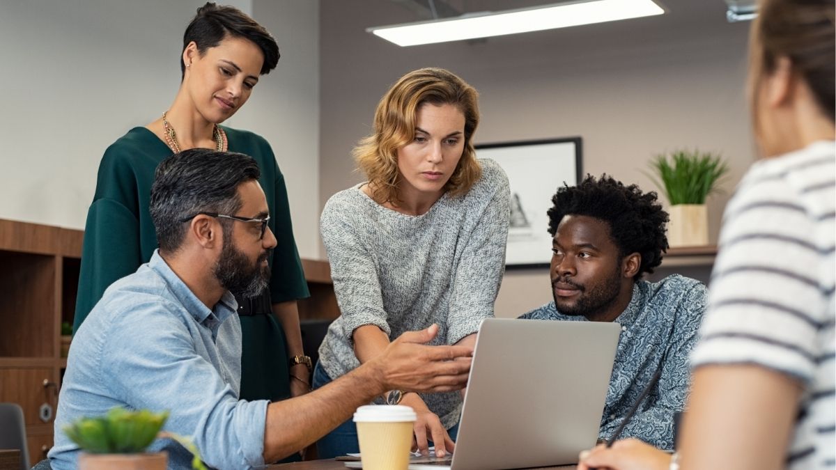 IT staffing professionals collaborating around a laptop, representing growth and teamwork in Denver’s expanding tech market for staffing firms.