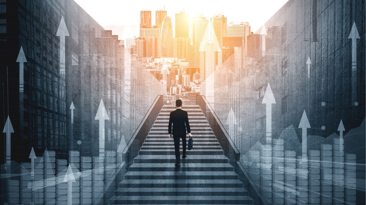Business professional walking up steps toward a city skyline with upward arrows and charts, symbolizing growth strategies and investment priorities for staffing companies.