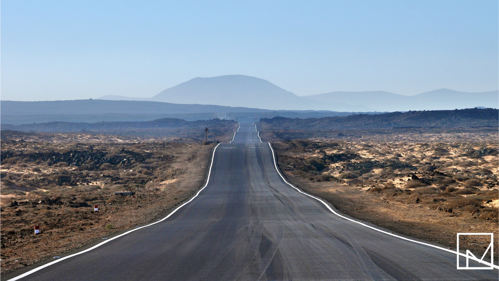 A long, empty road stretching through a desert landscape, symbolizing the 50-mile distance that unlocks tax-free per diem benefits for traveling contractors.
