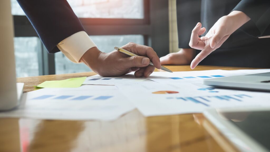 Business professionals reviewing financial reports and data, representing strategic consulting and advisory services for IT and technology staffing firms.