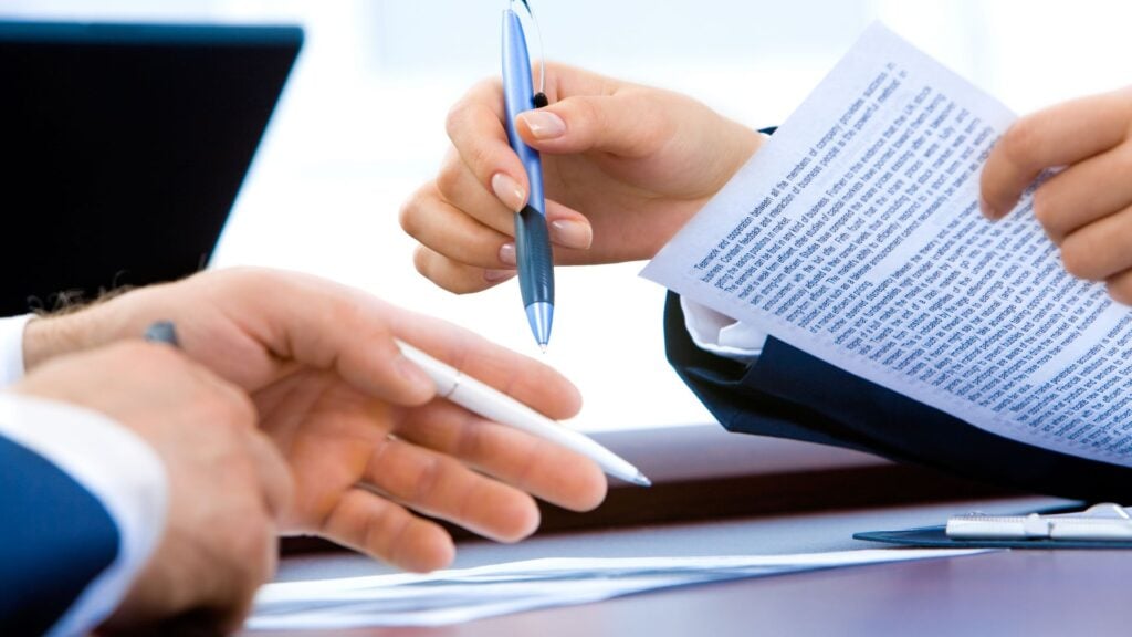 Business professionals reviewing and discussing a contract, representing financial staffing agreements and client engagements.