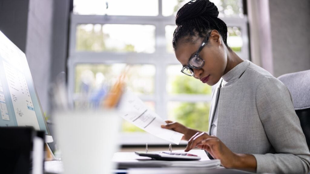 Financial professional reviewing reports and calculations, representing payroll funding and financial staffing operations.