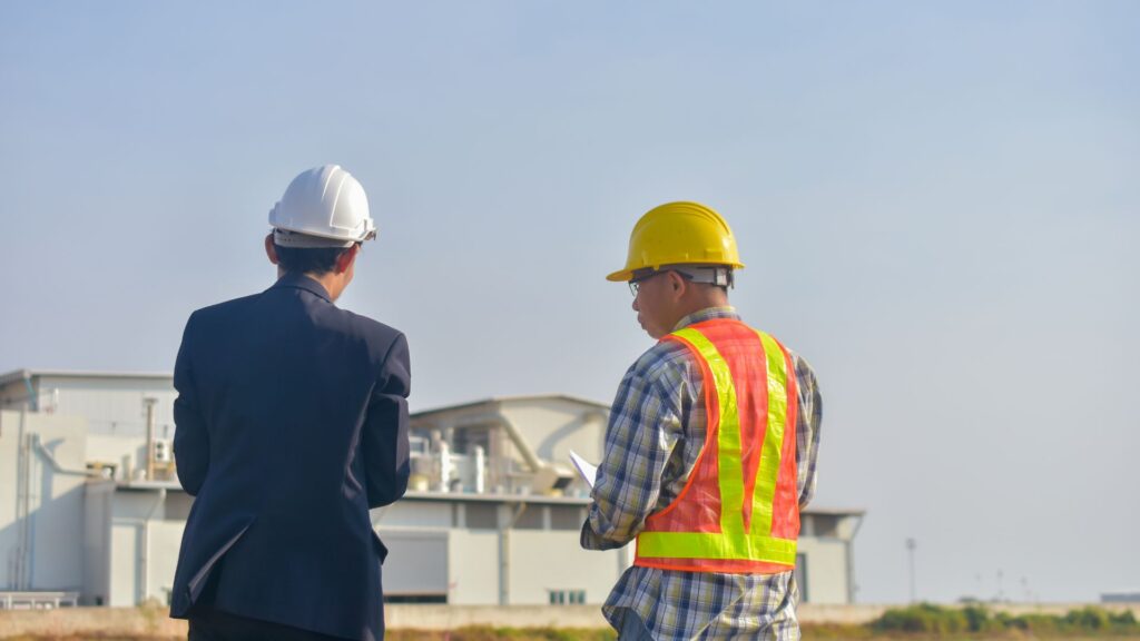 Engineers and project managers reviewing work at an industrial site, representing government contract staffing for infrastructure and operations projects.