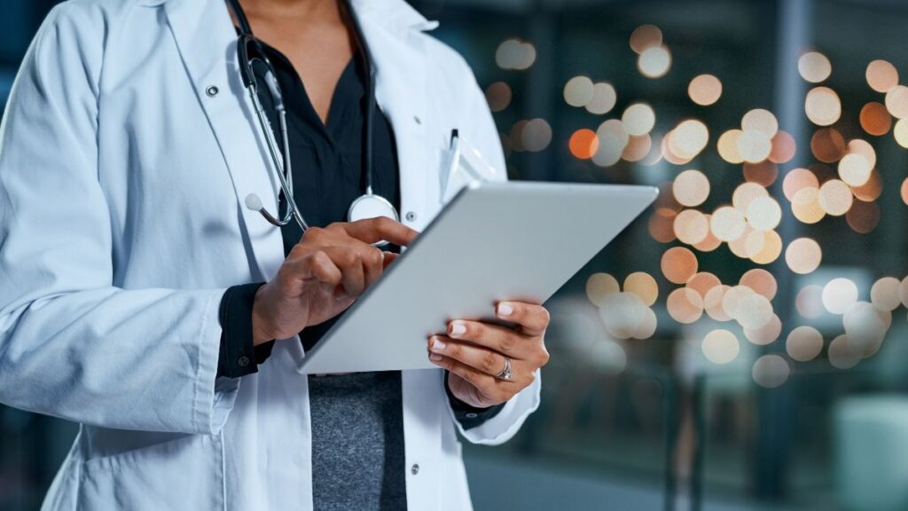Medical professional using tablet for healthcare staffing payroll and workforce management solutions.
