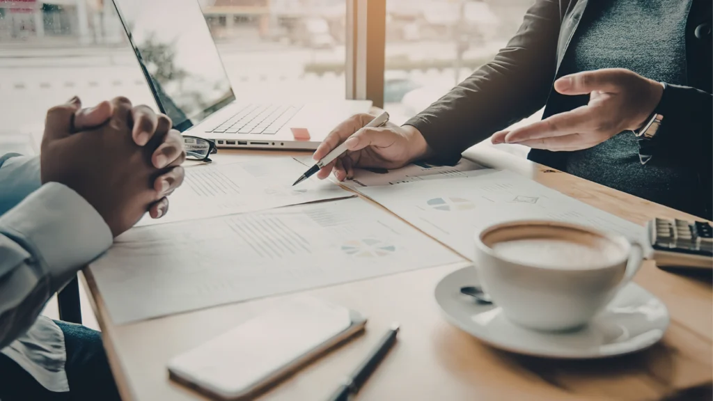 Business professionals reviewing documents and discussing payroll funding solutions during a consultation for staffing firm funding and rate quote request.