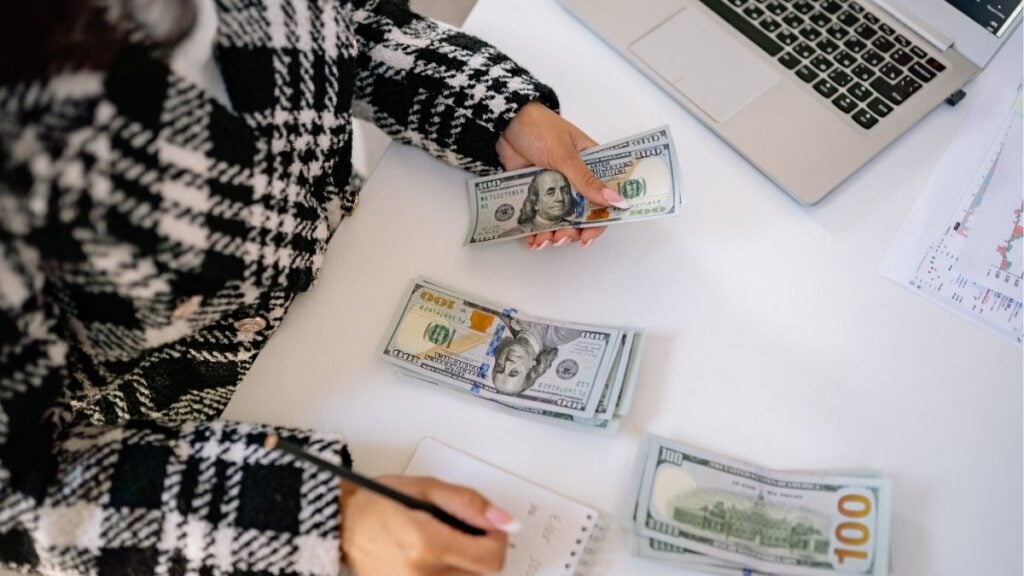 Counting cash and reviewing finances, illustrating cash flow gaps and the importance of collections support for staffing firms.