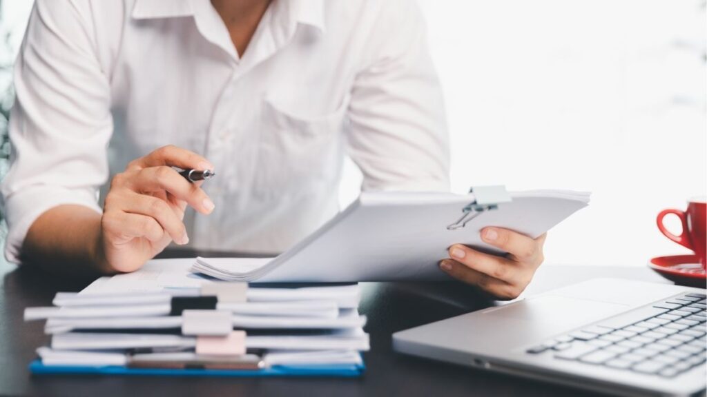 Professional reviewing payroll documents to manage staffing payroll tax processing, filings, and compliance across jurisdictions.