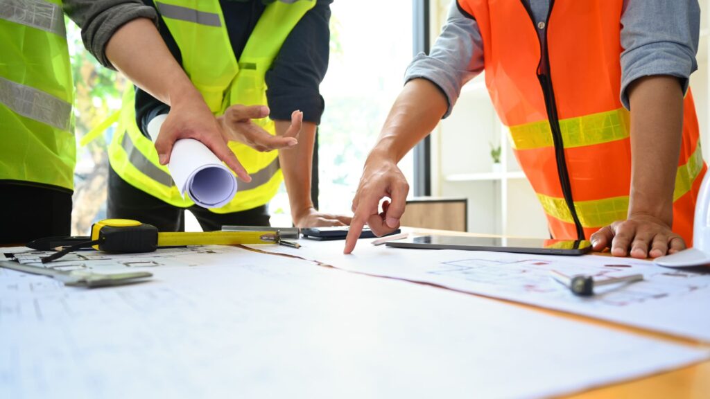 Construction team reviewing blueprints and plans at a job site, representing construction staffing and project-based workforce support.