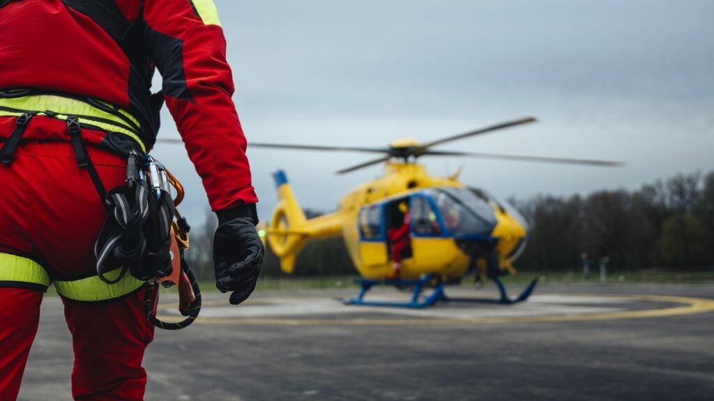 Emergency response worker walking toward rescue helicopter representing payroll funding for disaster recovery staffing firms and emergency response contractors.