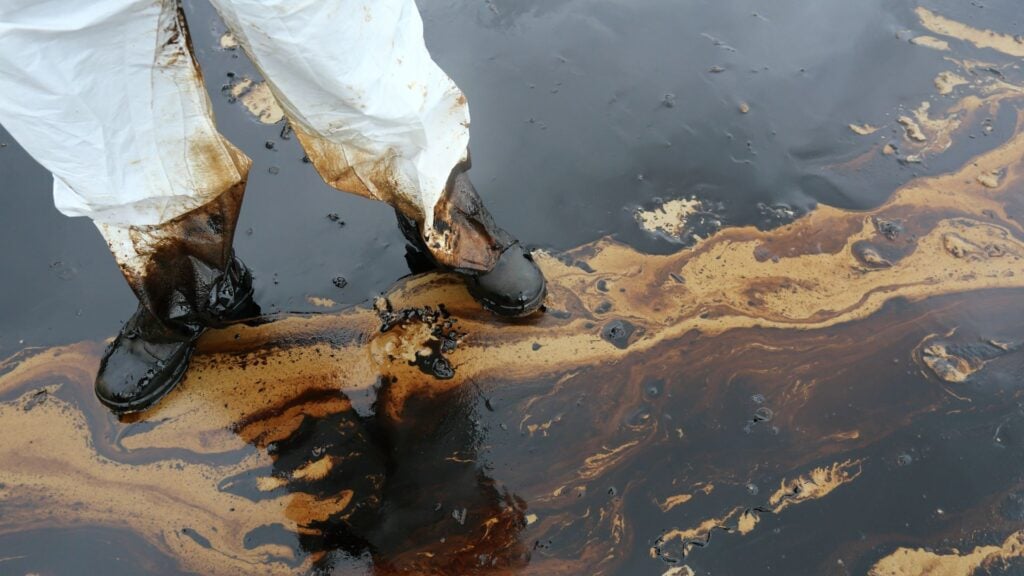 Environmental cleanup worker standing in contaminated water during disaster response operation representing payroll funding for disaster relief and emergency remediation staffing firms.