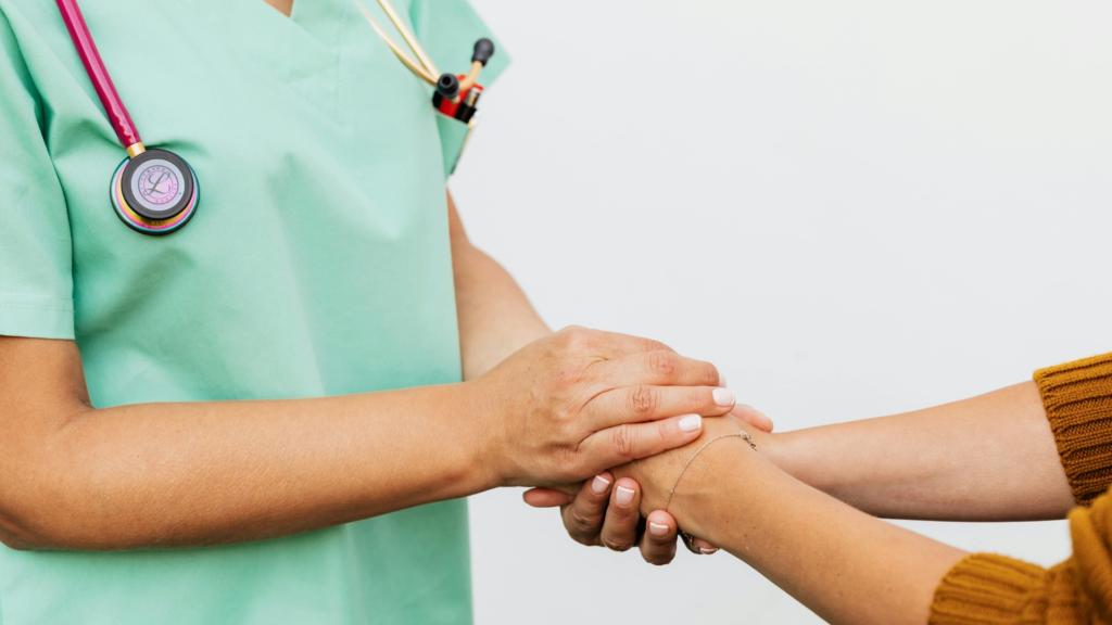 Healthcare professional in scrubs holding a patient’s hands, representing compassionate care and strong support in healthcare staffing partnerships.