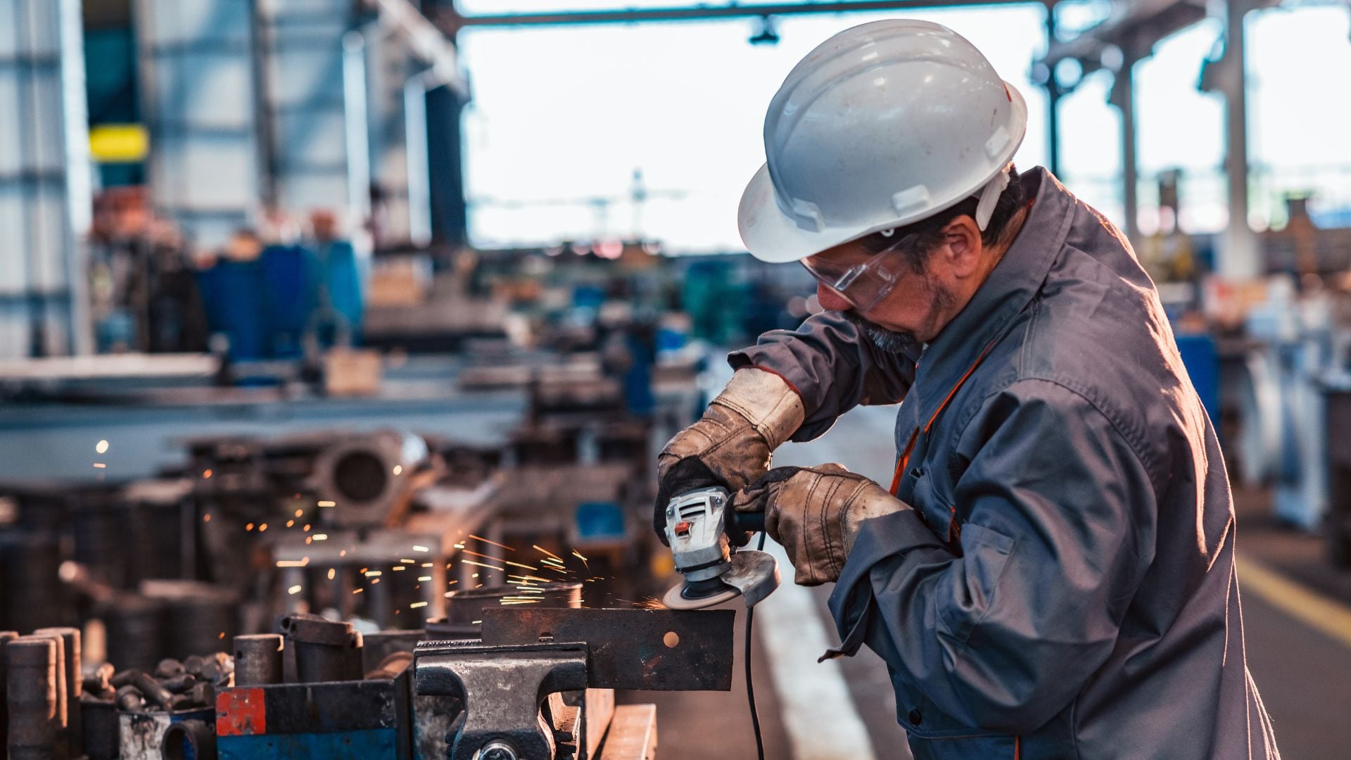 Metal fabrication worker operating an industrial grinder representing light industrial staffing in manufacturing and production environments.