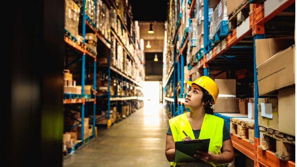Light industrial staffing worker in warehouse reviewing inventory and managing stock for efficient operations.