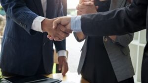 Business Acquisition Meeting for Staffing Agency Sale - Madison Resources - Madison Resources Business owners shaking hands after agreeing to the sale of a staffing agency during a business acquisition meeting.