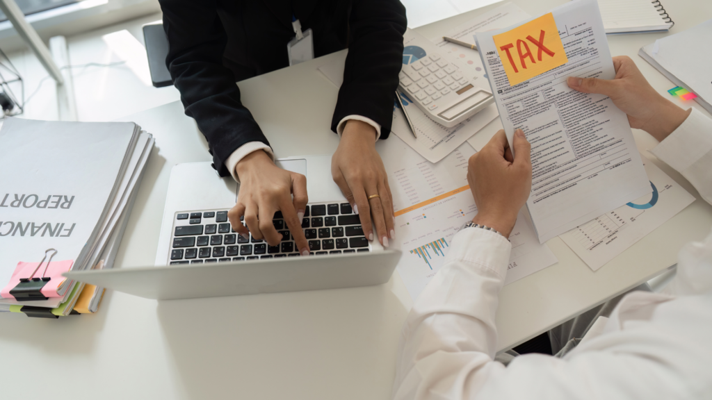 Two staffing company employees reviewing payroll tax forms and financial reports at a desk.