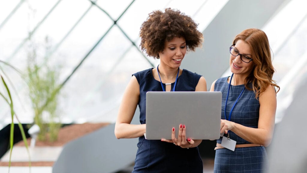 Two Madison Resources team members reviewing a staffing firm’s funding on a laptop, representing payroll funding and back office support for staffing firms.